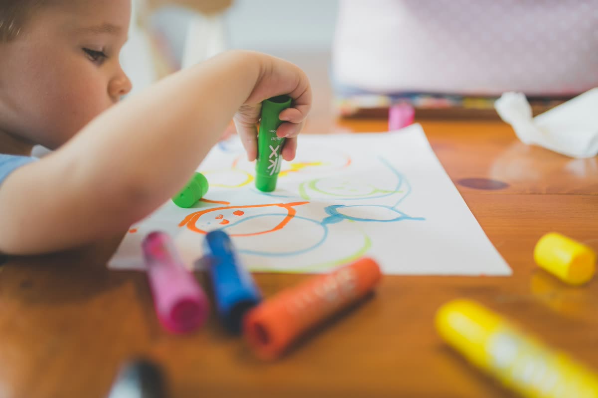 A young child drawing in crayon